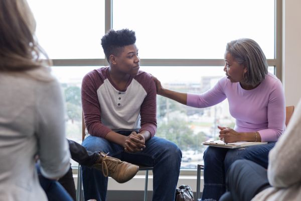 Afbeelding van een zorgprofessional die in gesprek is met een  jongere